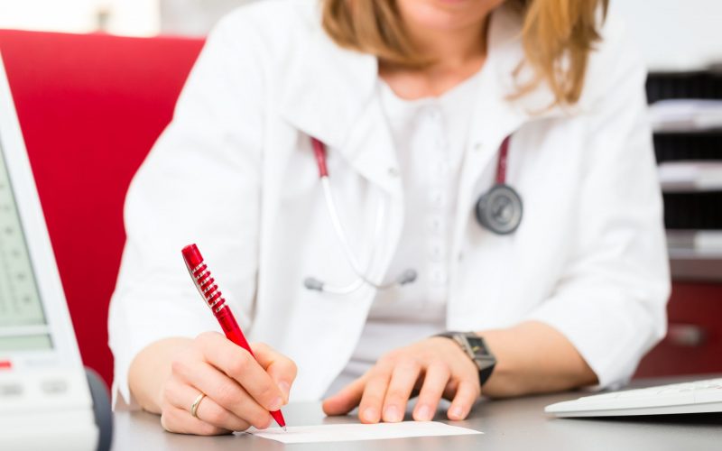 Doctor writing medical certificate in practice